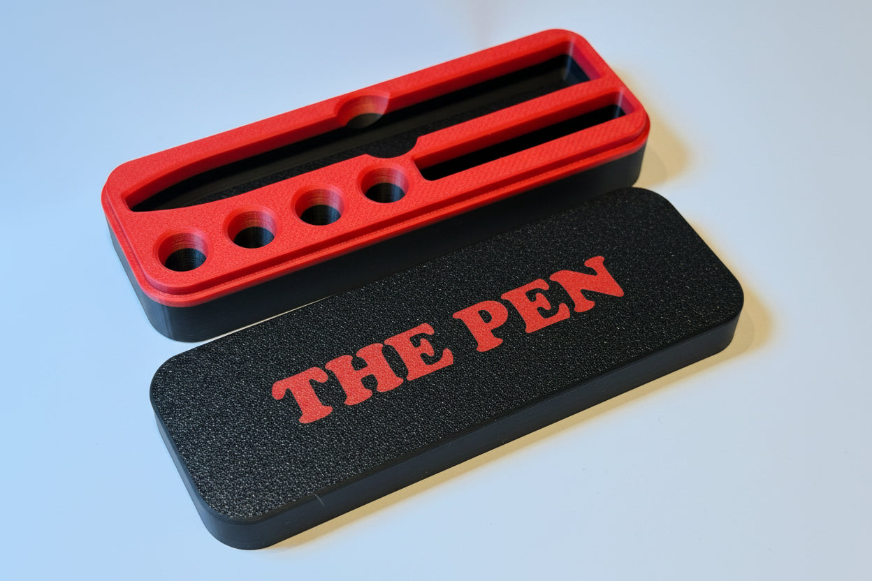 Black and red KwikPen case with 'THE PEN' engraving in a red on black background